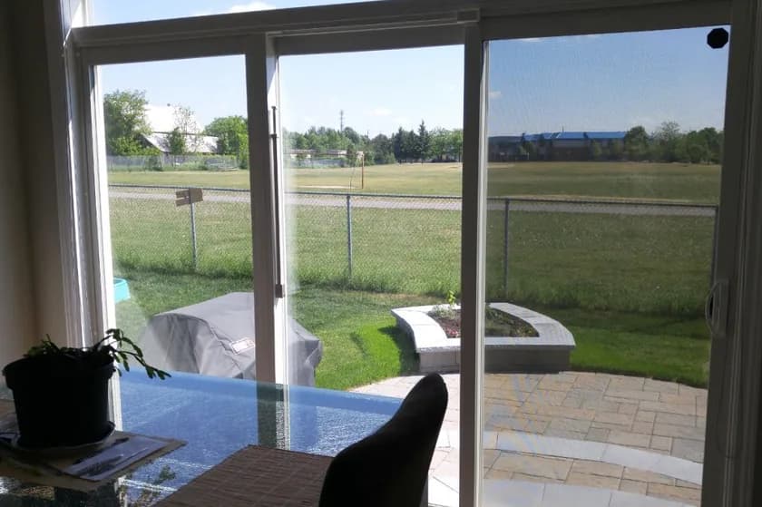 Solar control window film on sliding patio doors, cutting the glare and heat from a sunny backyard while keeping the view